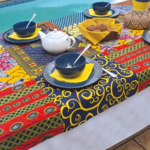 Handcrafted tablecloth with a vibrant multicolor patchwork-inspired design featuring intricate patterns and bold geometric shapes in various colors, spread out on a table.