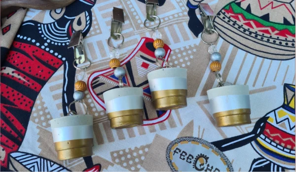 Close-up of a handcrafted African-inspired table runner with vibrant patterns, accompanied by four gold and silver dipped concrete weights, displayed on a decorative background