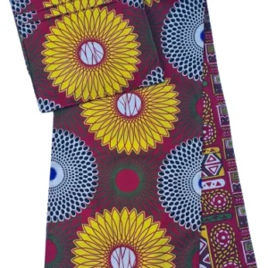 Handmade Africa-inspired reversible red and yellow table runner with four matching placemats set on a glass outdoor dining table, featuring vibrant sunburst patterns, yellow cups, black plates, and a woven decorative centerpiece.