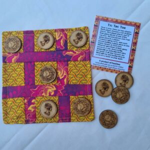 A vibrant tic-tac-toe board with African-inspired fabric design and wooden game pieces featuring unique carvings.